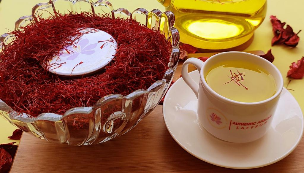 Afghan Super Negin saffron threads in a crystal bowl beside the branded Authentic Afghan Saffron teacup