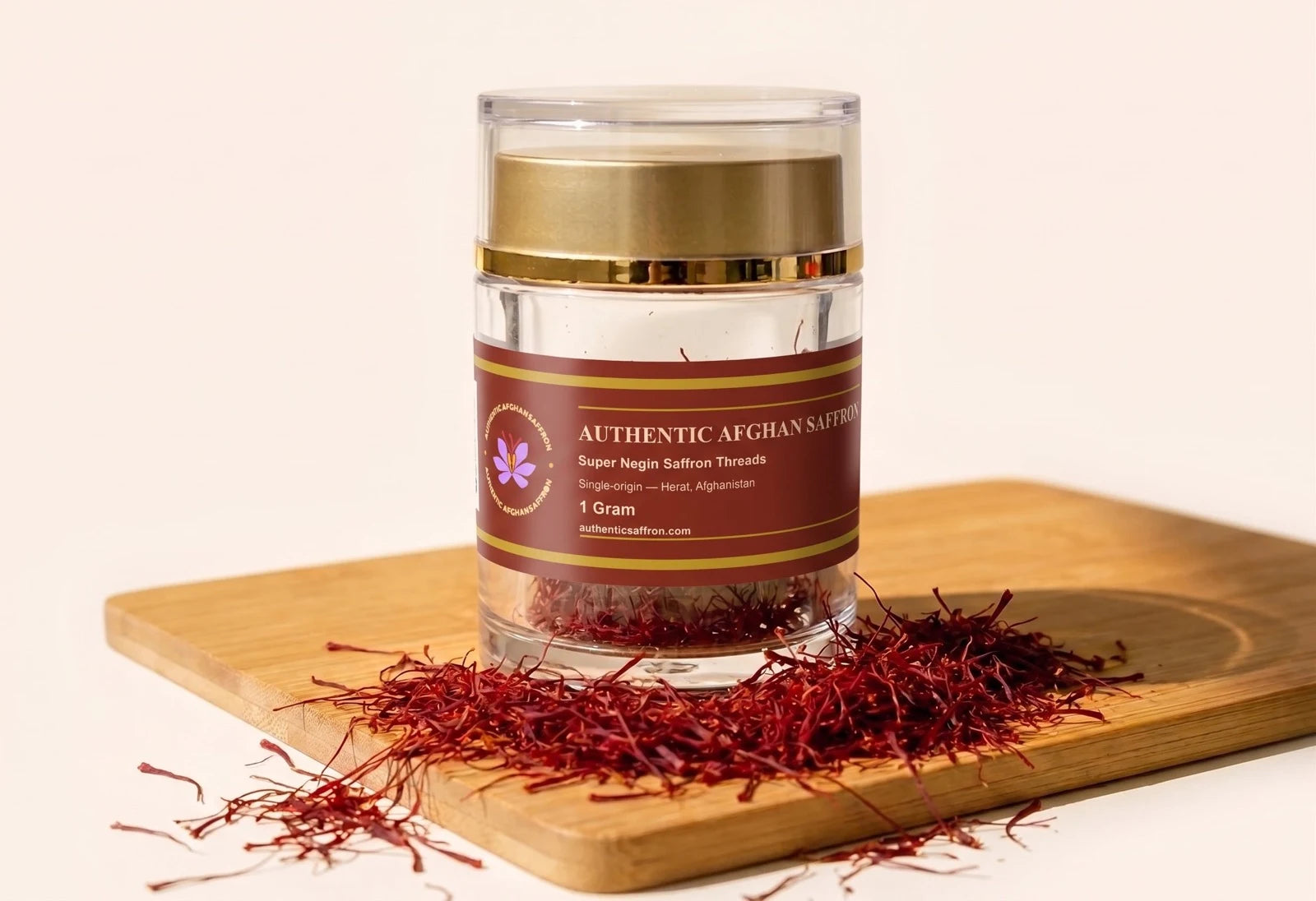 One gram of Authentic Afghan Super Negin saffron in its crystal jar on a bamboo board, with loose all-red Herati threads scattered around the base