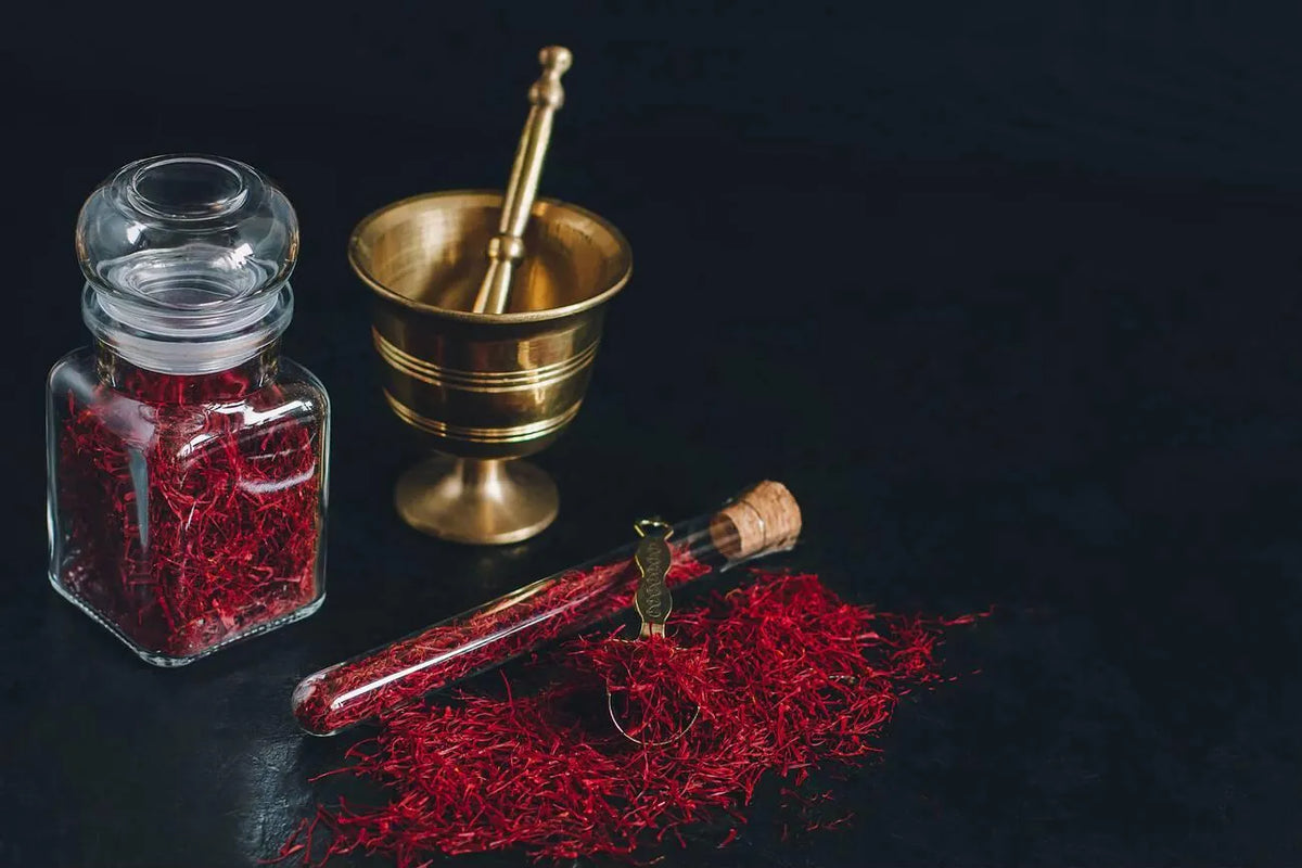 All-red Afghan saffron threads beside a brass mortar and pestle