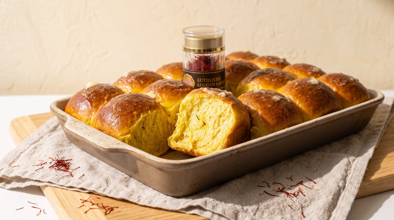 A tray of pull-apart saffron dinner rolls with golden crumb, one torn open, beside a jar of Authentic Afghan Saffron threads