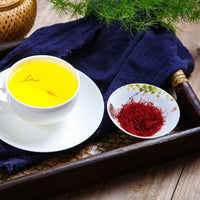Saffron tea bloomed to a deep gold in a white cup, showing the colour a few threads release